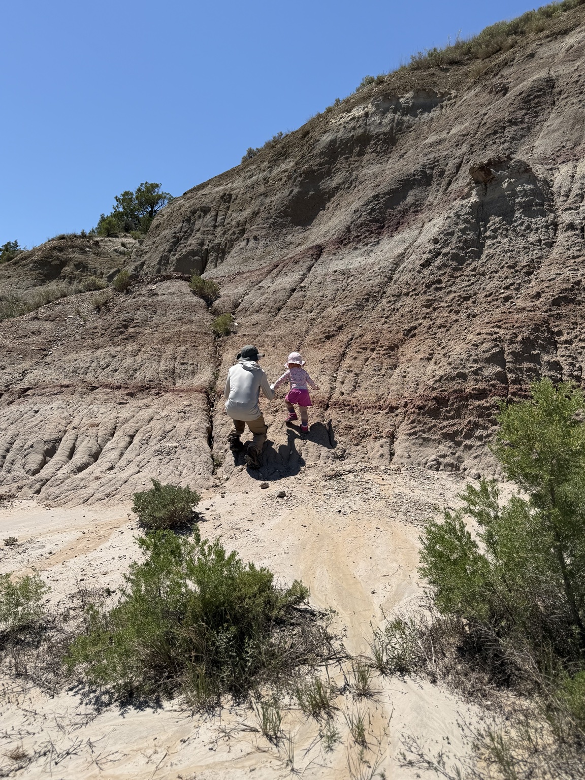 A father helping his young daughter climb in the North Dakota Badlands